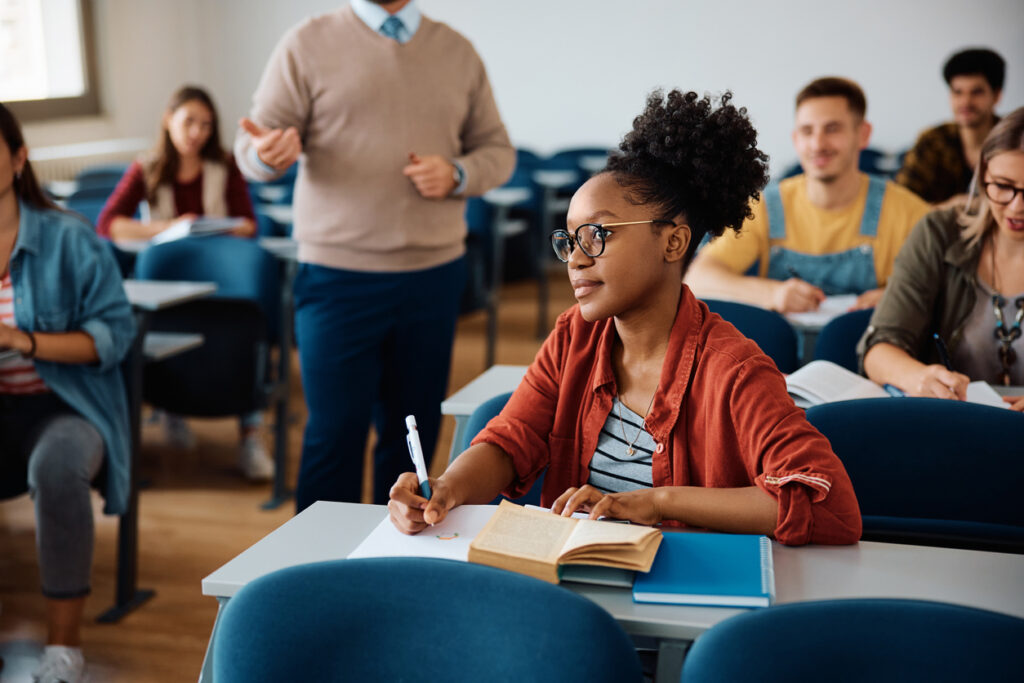 Black Female Student Taking Notes During A Class In Lecture Hall.